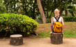© Artem Markin - A blonde with a yellow backpack sits in a green park. Wears a red bandage, arms with tattoos. Asia travel