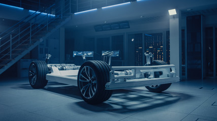Fototapete - Concept of Authentic Electric Car Platform Chassis Prototype Standing in Industrial Machinery Design Laboratory. Hybrid Axel Frame include Wheels, Suspension, Engine, Brakes and Battery. 