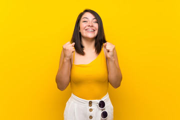 Young Mexican woman over isolated yellow background celebrating a victory in winner position