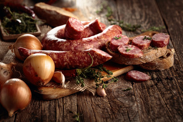 Wall Mural - Dry-cured sausage with bread and spices on a old wooden table.