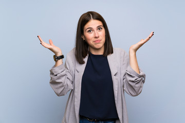 Wall Mural - Young woman over isolated blue wall making doubts gesture