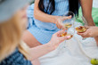 © spaskov - Three female hands with glasses of white wine. Toast, congratulations on an outdoor picnic. The concept of relaxation and companionship.