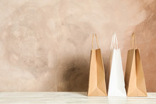 Paper Bags On White Table Against Brown Background, Copy Space