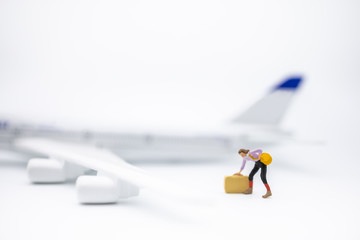 Wall Mural - Travel and transportation Concept. Close up of woman traveler miniature figure with baggage and shoulder bag standing on white background with mini toy airplane model and copy space.