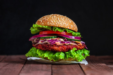 healthy vegan burger with beet patty coleslaw salad cucumber tomato lettuce on dark wooden background 