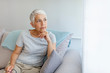 © Dragana Gordic - Sad Mature Woman Suffering From Agoraphobia Looking Out Of Window. Depressed senior woman sitting on sofa at home. Depressed senior woman at home