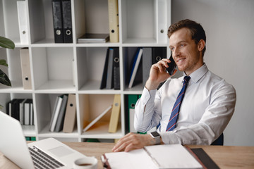 Wall Mural - Relaxed man talking on the phone at work and smiling