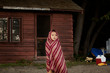 © Cavan for Adobe - Girl wrapped in blanket standing in front of log cabin