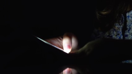 Woman hand using mobile phone in the dark