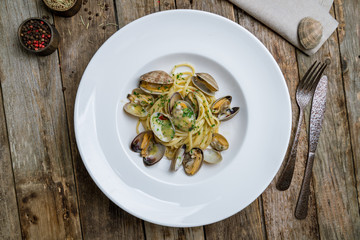 Wall Mural - Spaghetti with vongole in wine sauce on wooden background