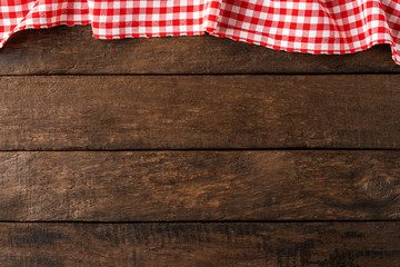 Wall Mural - Red checkered tablecloth on wooden background. Top view