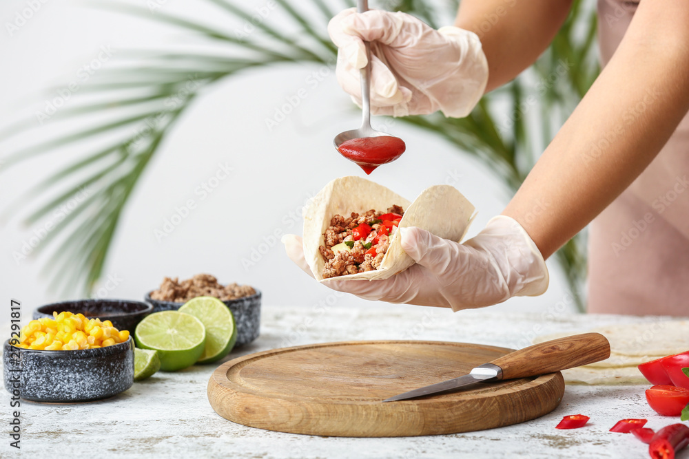 Woman preparing tasty fresh tacos in kitchen