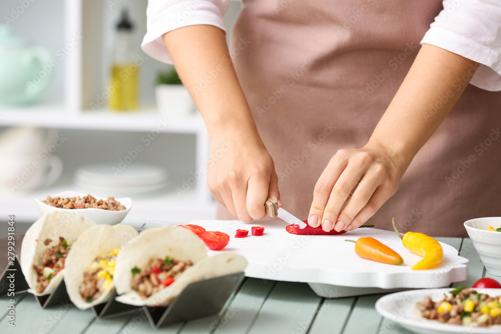 Woman preparing tasty fresh tacos in kitchen