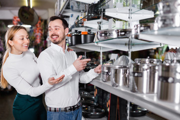 Wall Mural - Young couple choosing new saucepan in dinnerware store