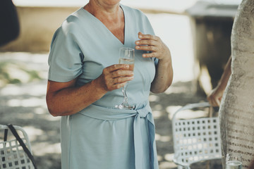 Wall Mural - Mother performing speech at wedding reception for daughter bride and toasting with champagne. Stylish old woman holding glass of champagne and cheering