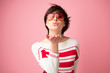 Young pretty woman looking at camera with love gesture kiss. Happy young woman in sun glasses ready to give kiss over pink background