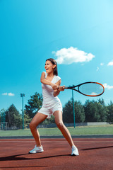 Wall Mural - Dark-haired woman screaming while hitting the tennis ball