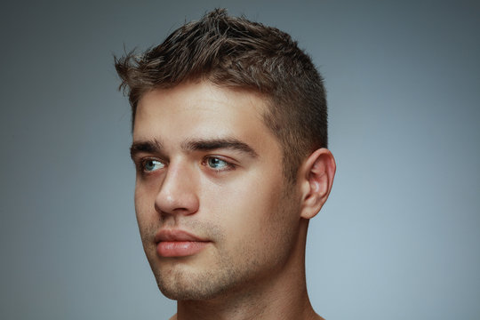 Portrait of shirtless young man isolated on grey studio background. Caucasian healthy male model looking at side and posing. Concept of men's health and beauty, self-care, body and skin care.