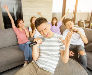 Group of friends playing karaoke at home