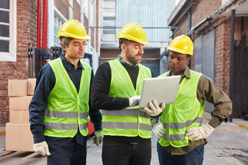 Three logistics workers with laptop computer