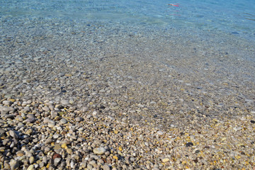 Wall Mural - Sea stones in the sea water. Pebbles under water. The view from the top. Nautical background. Clean sea water. Transparent sea.