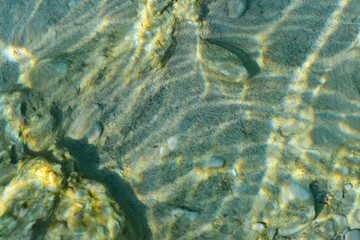 Wall Mural - Top view of transparent clear water of river or creek with pebble stones. Abstract nature background