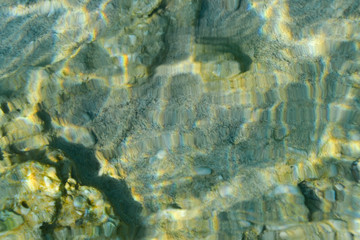 Wall Mural - Top view of transparent clear water of river or creek with pebble stones. Abstract nature background