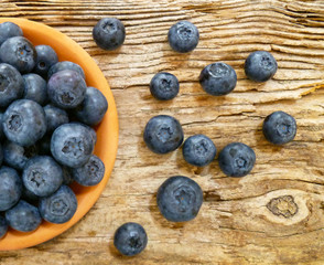 Bowl of fresh blueberries on rustic wooden old table. Freshly picked blueberries in bowl. Healthy organic fruit background. Organic food raw blueberries and mint leaf for healthy lifestyle.