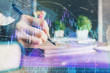 © peshkova - Financial forex charts displayed on woman's hand taking notes background. Concept of research. Double exposure