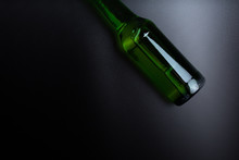 Green Glass Bottle On Black Desk Surface Top View
