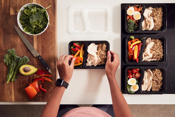 Wall Mural - Overhead Shot Of Woman Preparing Batch Of Healthy Meals At Home In Kitchen