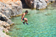 © Daniel CHETRONI - Little boy jumping off cliff into the ocean. Summer fun lifestyle. Brave kid