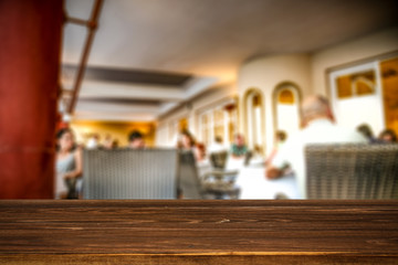 Wooden table top background in the rastaurant. Blurred restaurant view. Wooden top board empty space for an advertising product.