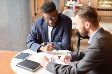 Two businessmen having a meeting in the cafe at the table.