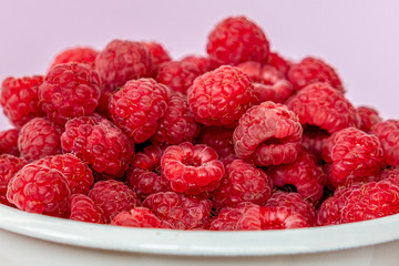 Wall Mural - Fresh organic raspberries in a white metal bucket on pink background