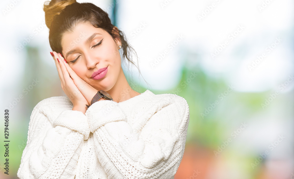 Young beautiful woman wearing winter sweater sleeping tired dreaming and posing with hands together while smiling with closed eyes.