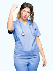 Sticker - Young adult doctor woman wearing medical uniform angry and mad raising fist frustrated and furious while shouting with anger. Rage and aggressive concept.