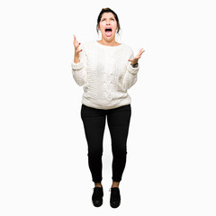 Poster - Young beautiful woman wearing winter sweater crazy and mad shouting and yelling with aggressive expression and arms raised. Frustration concept.