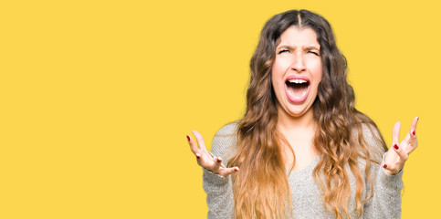 Poster - Young beautiful woman wearing winter dress crazy and mad shouting and yelling with aggressive expression and arms raised. Frustration concept.