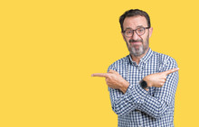 Handsome Middle Age Elegant Senior Man Wearing Glasses Over Isolated Background Pointing To Both Sides With Fingers, Different Direction Disagree