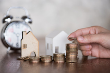 woman hand stacking dollars coins with a house model.save and investment for buy house concept .for the future.