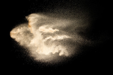 Wall Mural - Abstract sand cloud.Golden colored sand splash agianst dark background.Yellow sand fly wave in the air. Sand explode on black background ,throwing freeze stop motion concept.