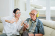 © Creativa Images - Woman and elderly man listening to music