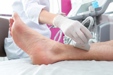 Wall Mural - Doctor conducting ultrasound examination of patient's leg in clinic, closeup