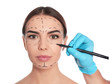 © New Africa - Doctor drawing marks on woman's face for cosmetic surgery operation against white background
