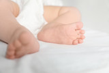 Fototapeta Koty - Little baby with cute feet on bed sheet, closeup
