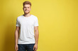 Young man wearing blank t-shirt on yellow background. Mockup for design