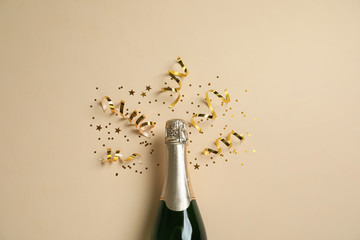 bottle of champagne with gold glitter and confetti on beige background, flat lay. hilarious celebrat