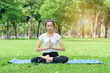 © Anucha - Young Asian woman practicing yoga pose at the park , Photo concept for Yoga Sport and Healthy lifestyle.