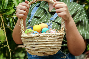 Wall Mural - Woman holding a wooden basket with many Easter eggs. Festival